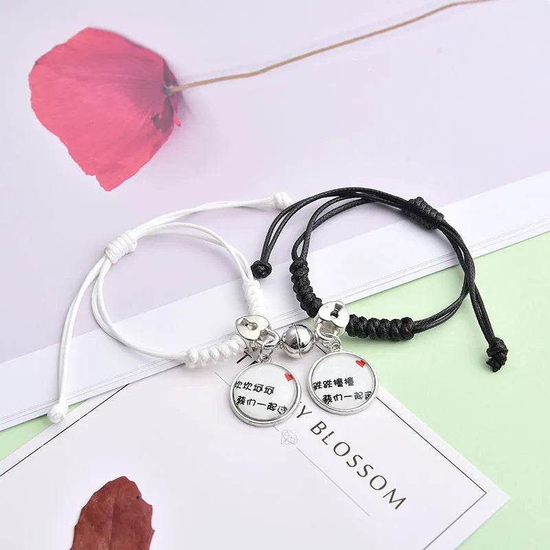Pair of magnet couple bracelets with suction clasp on wrist, showing alloy designs like crown and love lock.