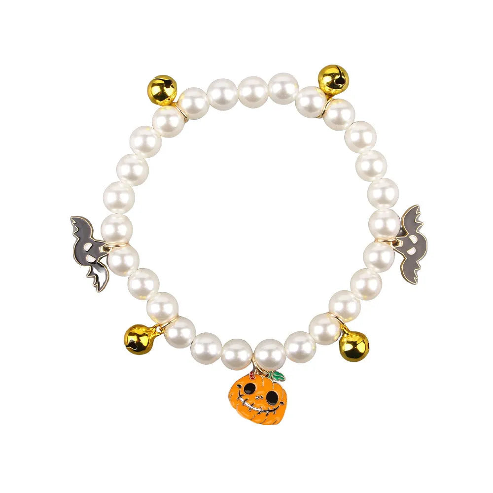 Purple simulated pearl cat collar with three Halloween pumpkin charms: ghost, skull, and smiley face.