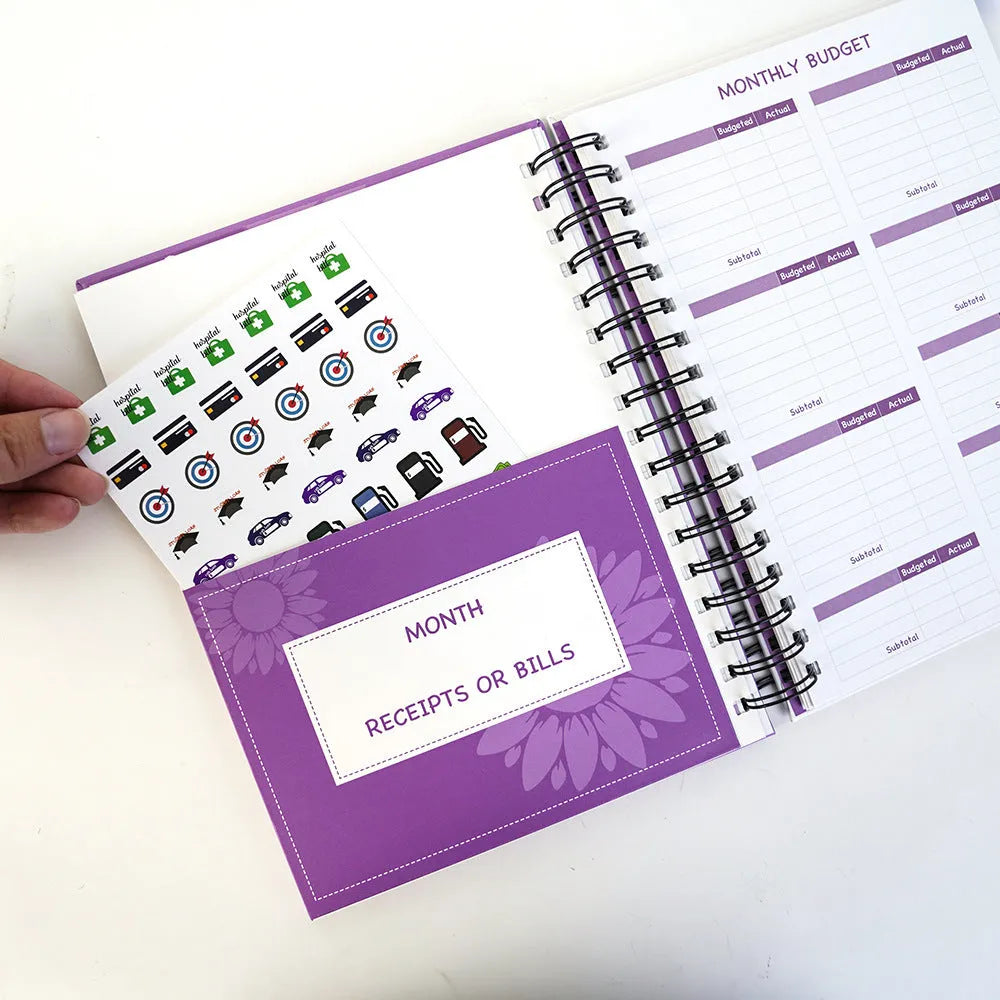 J12 purple coil-bound financial planning notebook with pen, stickers, and paper clips