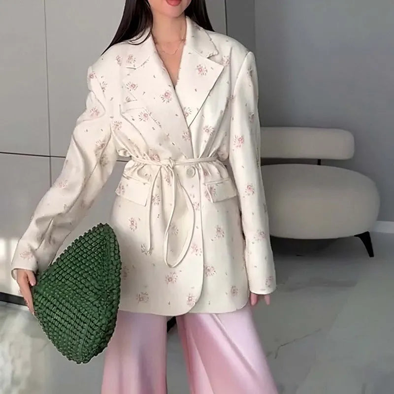 Women's white blazer with a lace-up fastening detail at the waist, shown on a hanger.