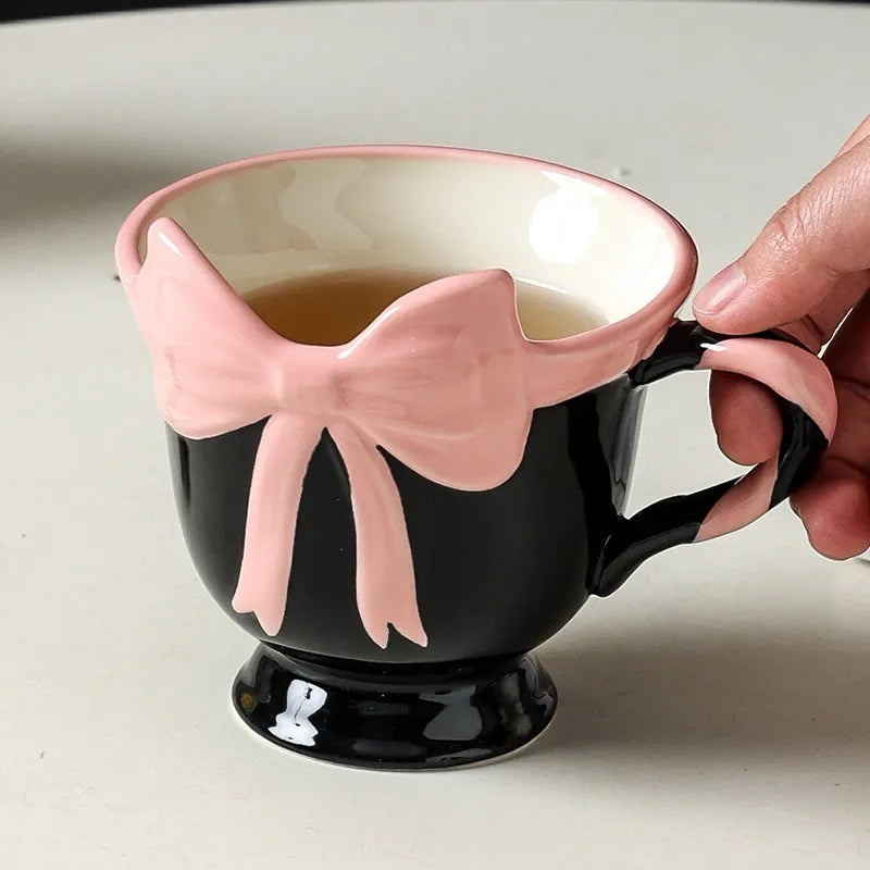 Ceramic mug with a pink and white girl's heart bow decoration on the side.
