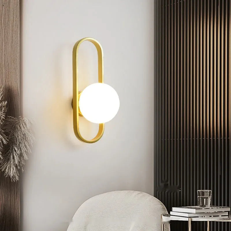 Modern minimalist wall lamp with glass shade and iron body in black or gold finish.