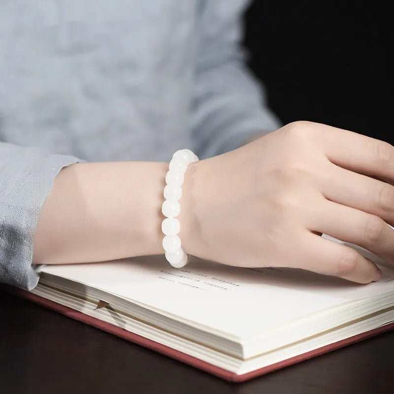 White Hetian jade barrel bead bracelet for men and women on a wrist, showing three bead size options.