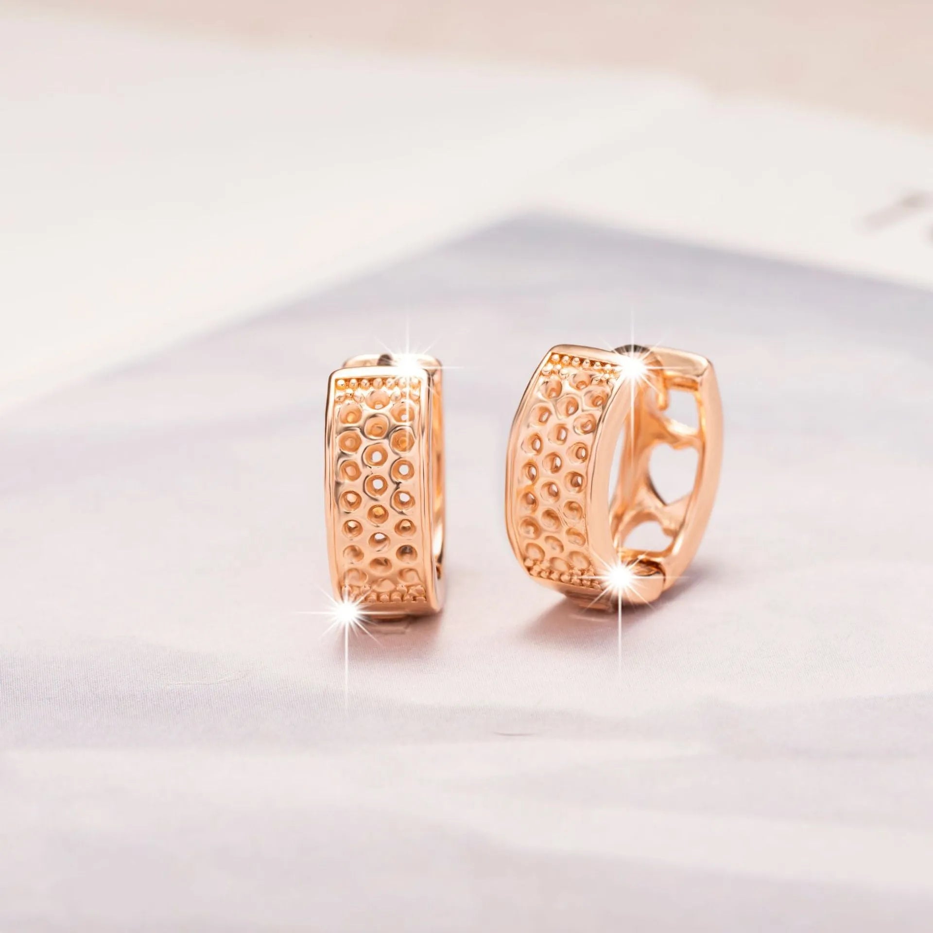 Rose gold electroplated earrings with three hollow heart shapes in circular design