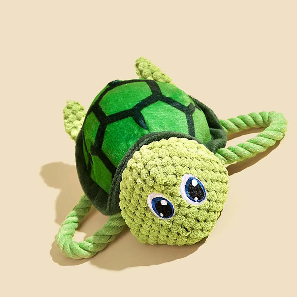 Green turtle-shaped plush dog chew toy with a knotted rope visible inside, on a white background.