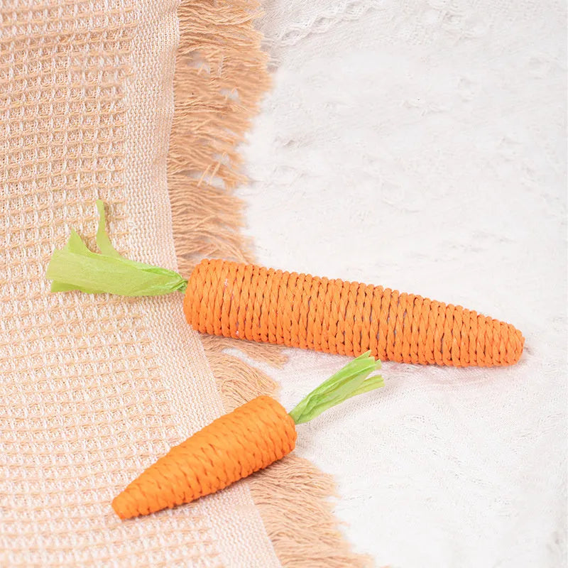 Assortment of cat toys including paper carrots, plastic ringing stones, and wooden grinding sticks on a plain background.