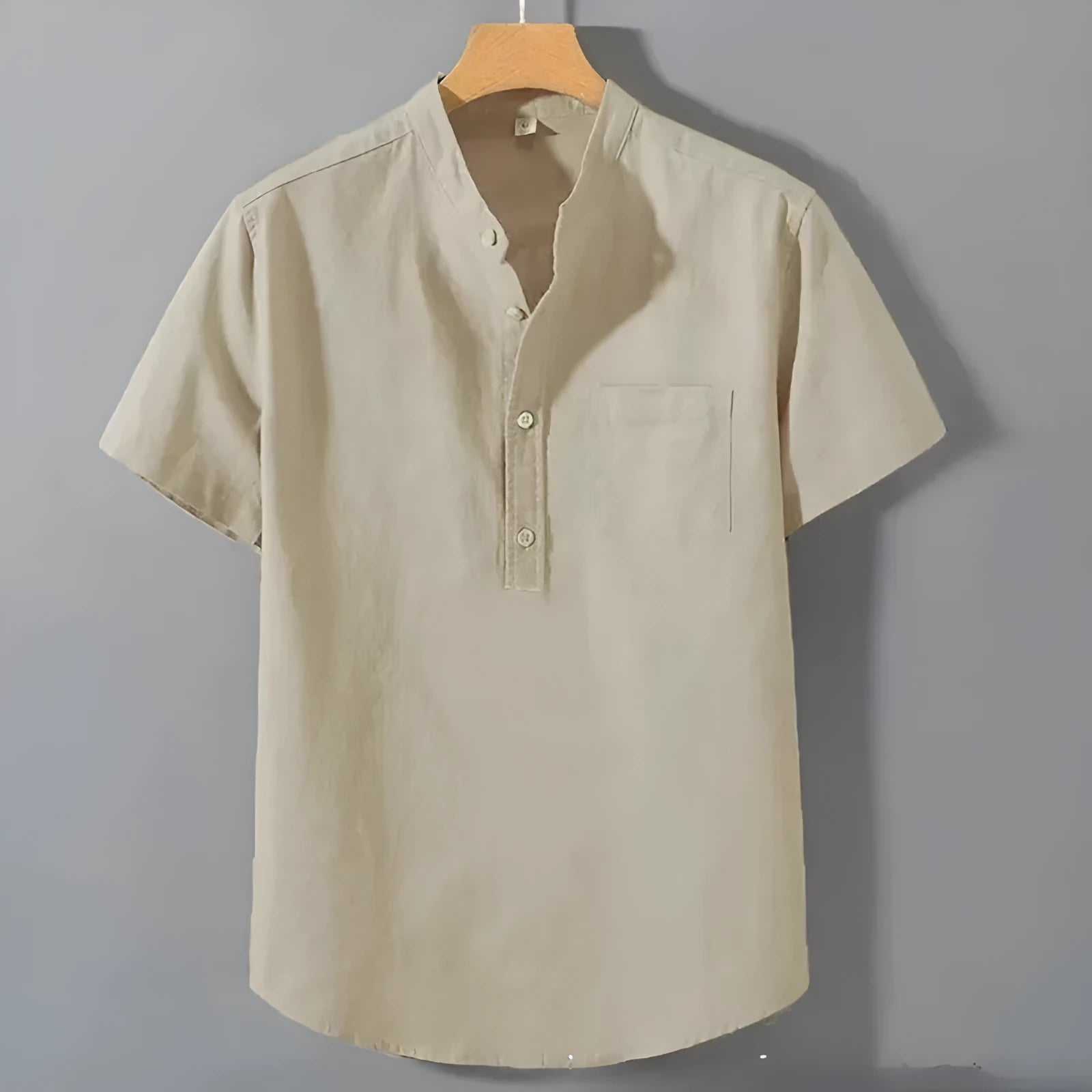 Man wearing a beige loose-fit linen shirt with a stand collar and short sleeves.