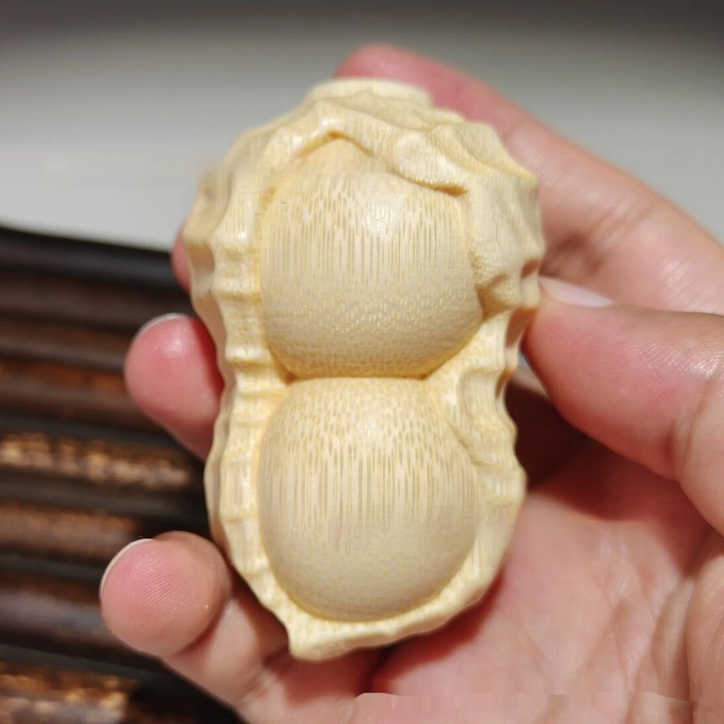 Carved solid bamboo peanut ornament in a modern simplicity style on a plain background.