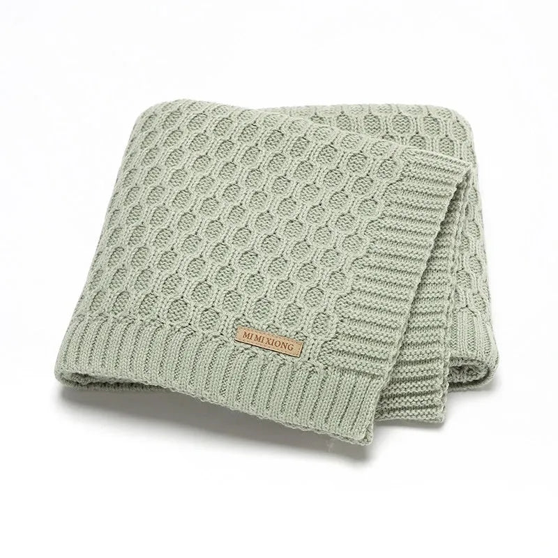 Solid colour infant hug blanket with three-dimensional line texture, shown in a choice of colours.