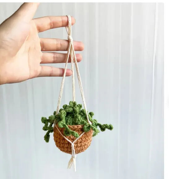 Green and white knitted wool car plant decoration with white hanging rope.