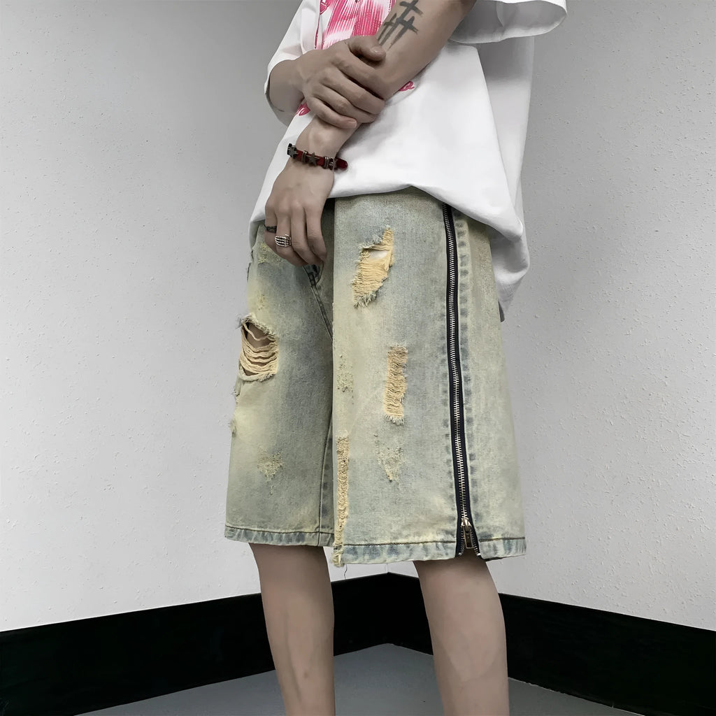Men's blue denim shorts with yellow mud wash effect, ripping details, button fly, and loose straight-leg fit