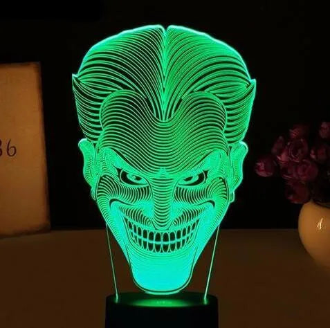 A clear acrylic 3D LED table lamp displaying gradient colours, standing on a square base with a USB cable and remote control.