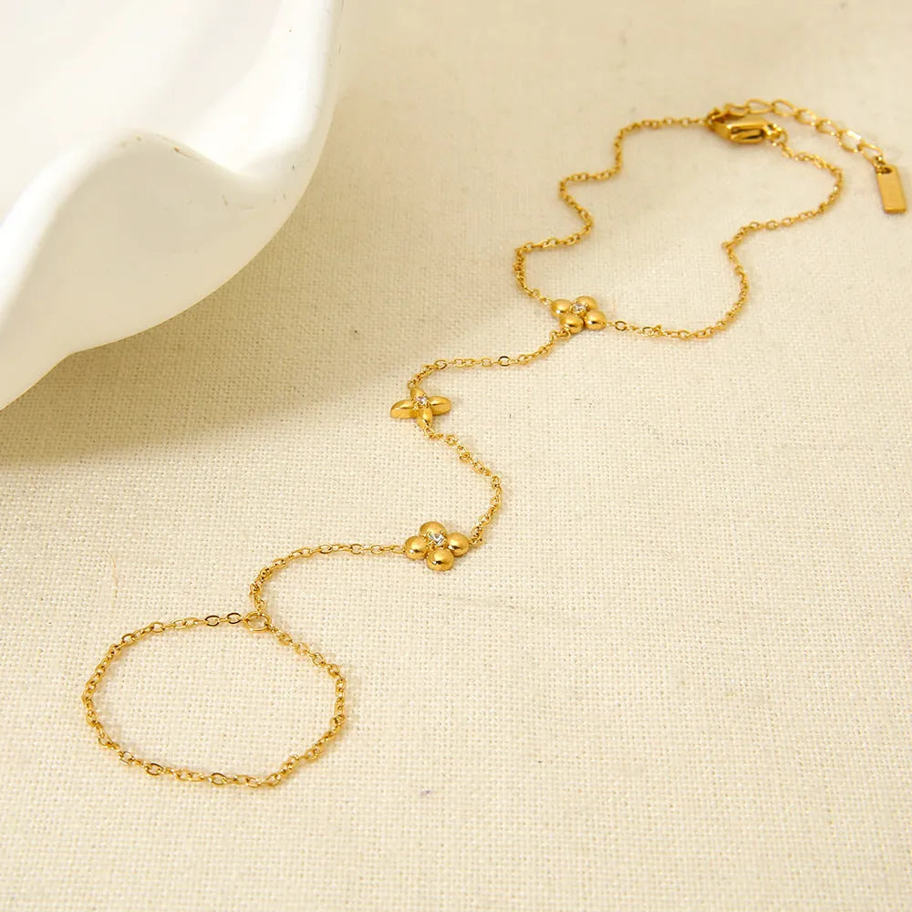 Gold stainless steel women's bracelet with geometric shape, flower and eight-pointed star details.