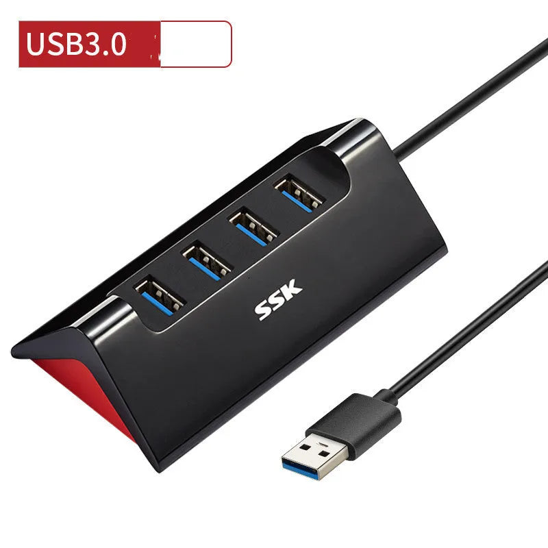 Black USB expansion dock with 4 ports on a desk next to a laptop.