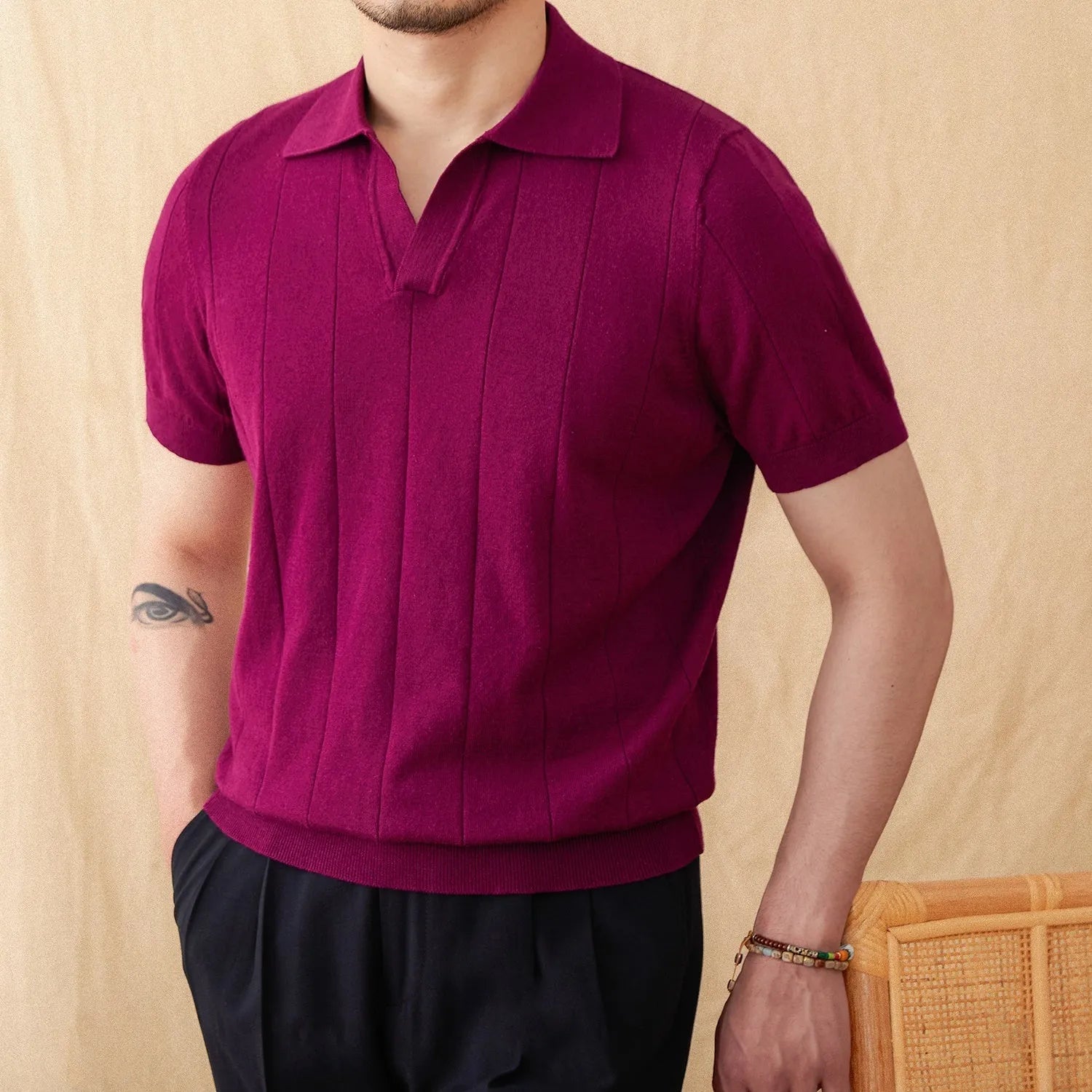 Man modelling a purple short sleeve polo shirt with a sunken stripe knit pattern and a seagull collar.