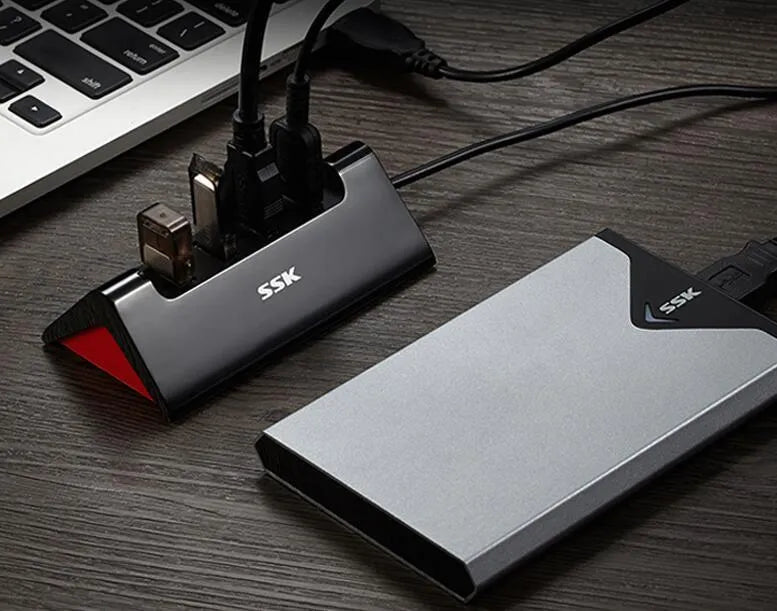 Black USB expansion dock with 4 ports on a desk next to a laptop.