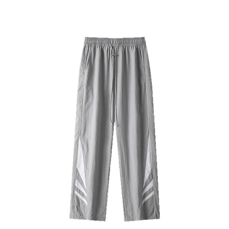 Men's black straight leg loose fit summer sports trousers with an elastic waist on a grey background.