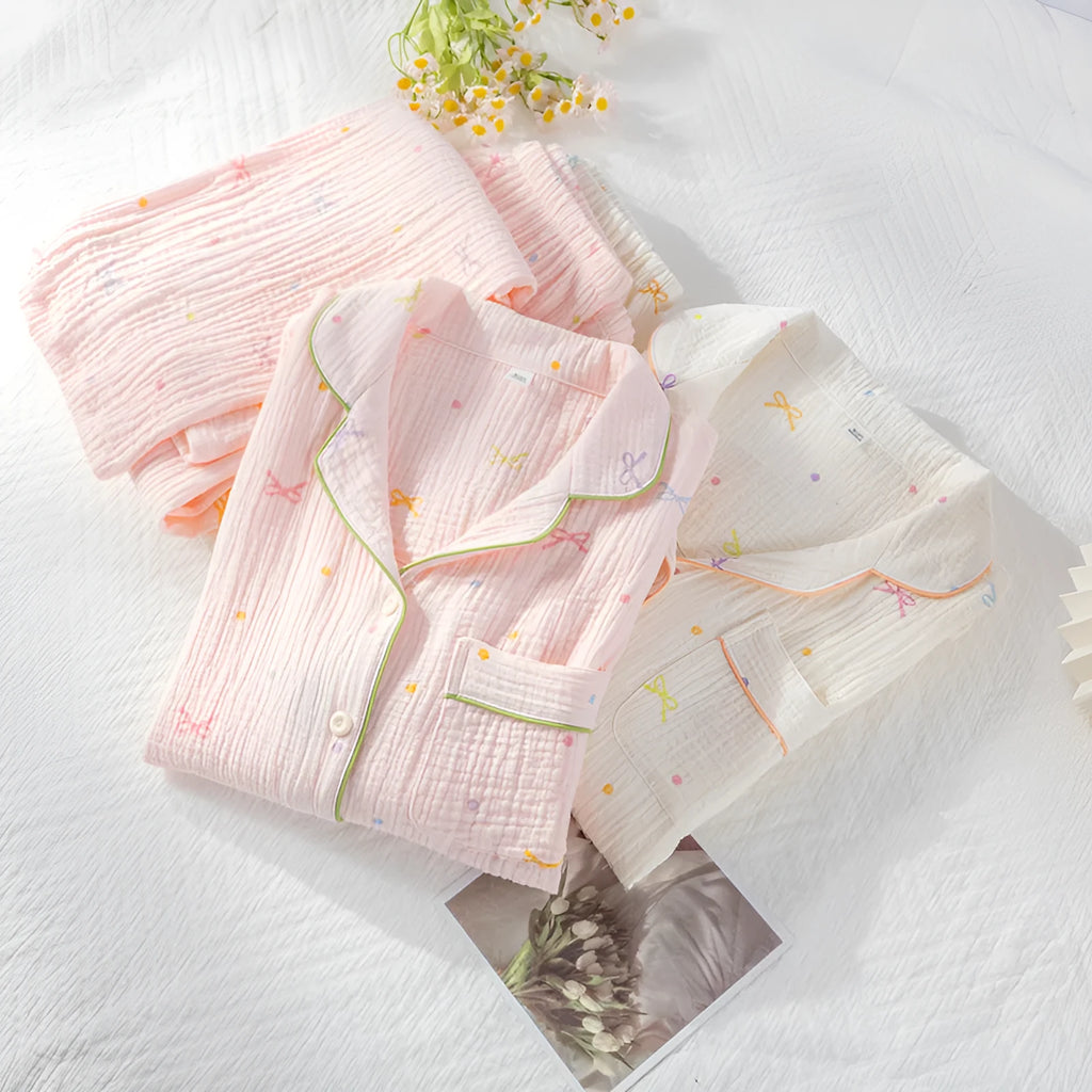 Women's beige long sleeve cotton pajama top and trousers set laid flat.