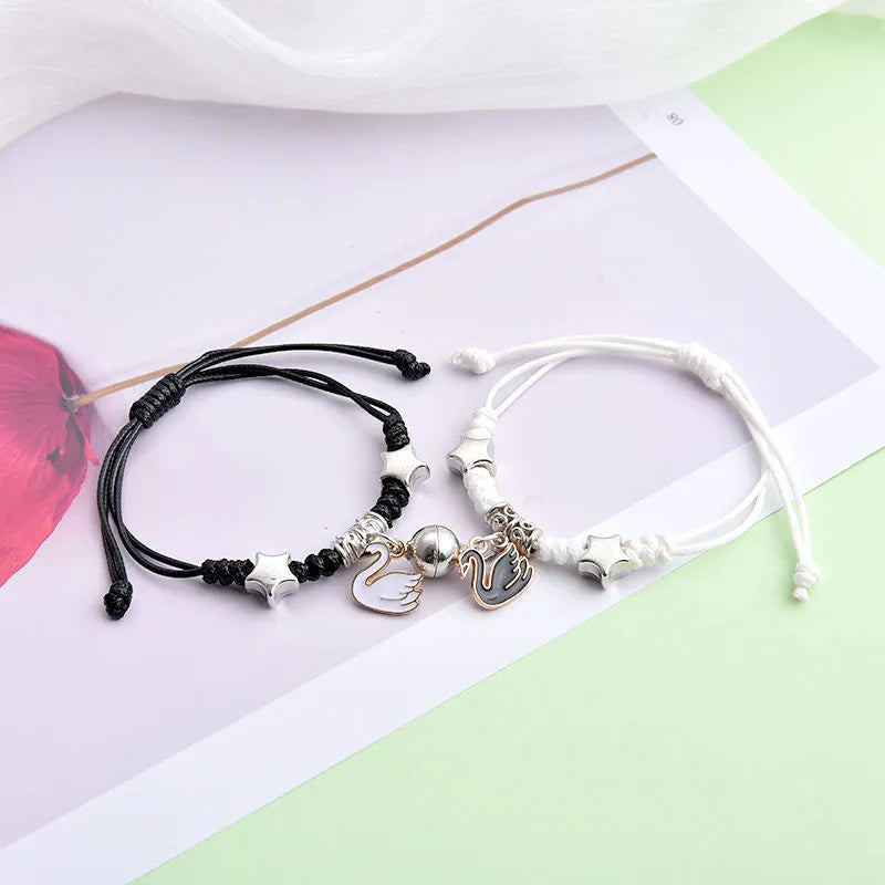 Pair of magnet couple bracelets with suction clasp on wrist, showing alloy designs like crown and love lock.