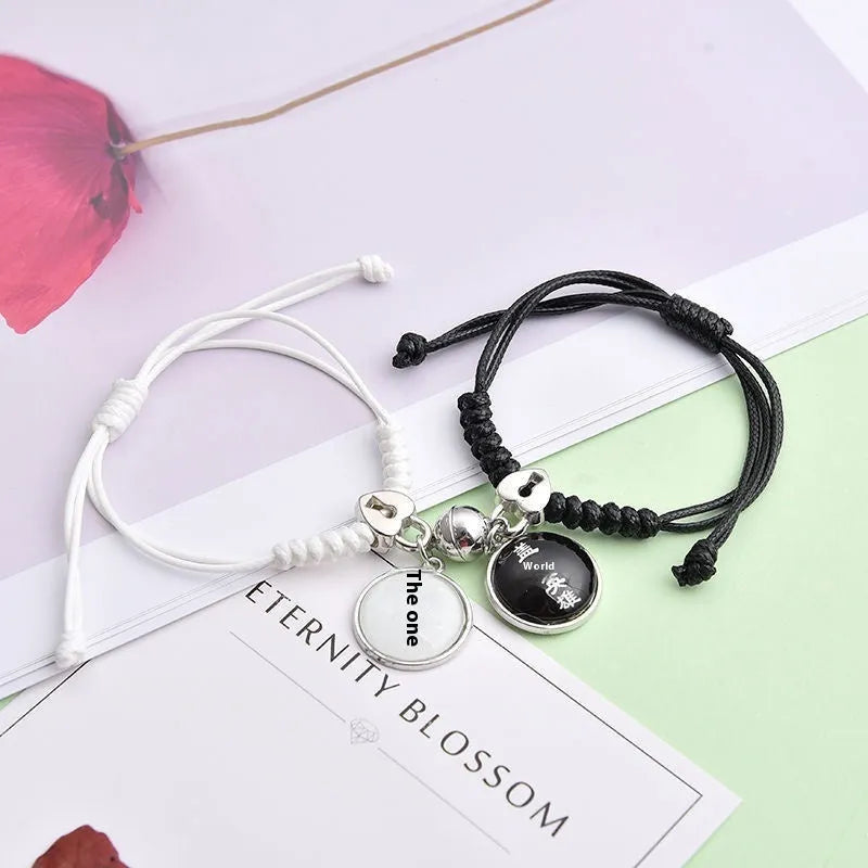 Pair of magnet couple bracelets with suction clasp on wrist, showing alloy designs like crown and love lock.
