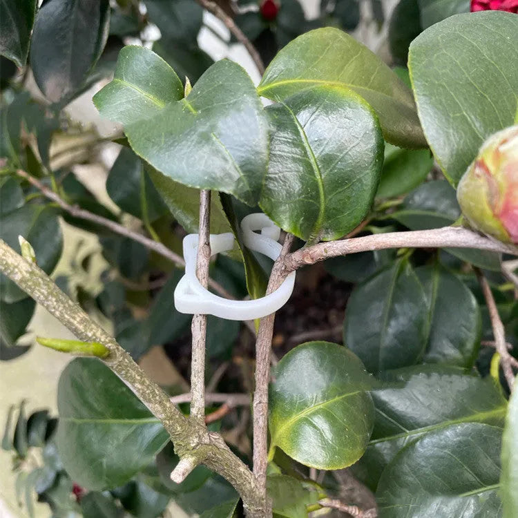 Red cat-shaped plastic gardening clip for plant support on green leaves