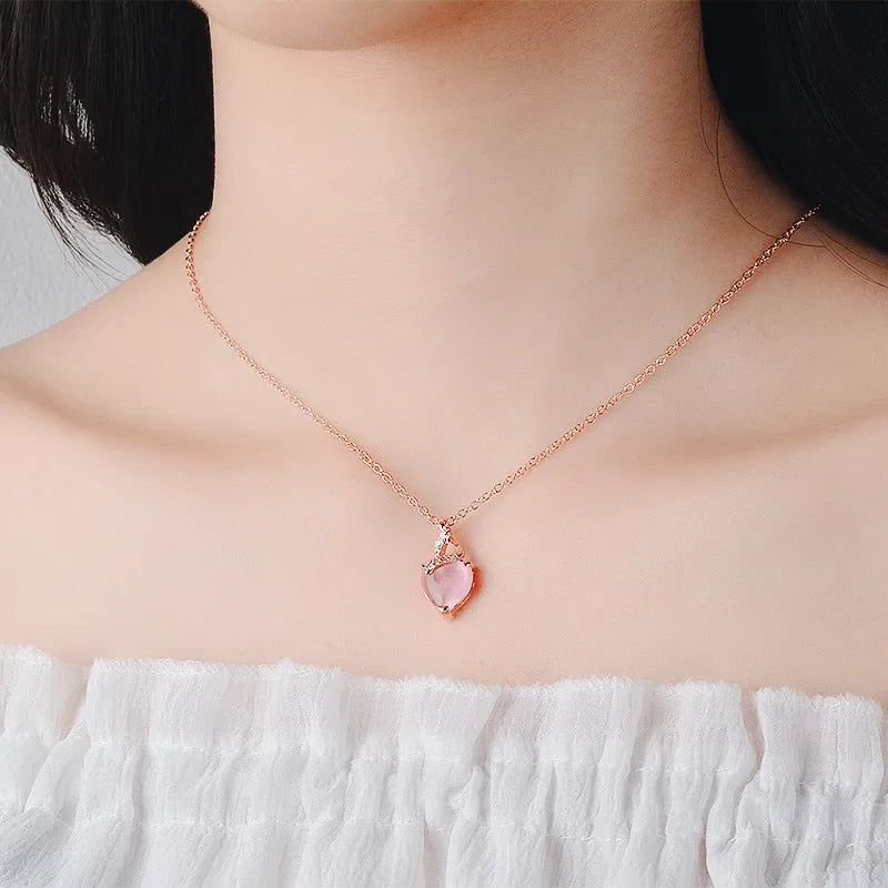 Rose gold heart-shaped pendant necklace with a pink synthetic crystal centre on a matching cross chain.