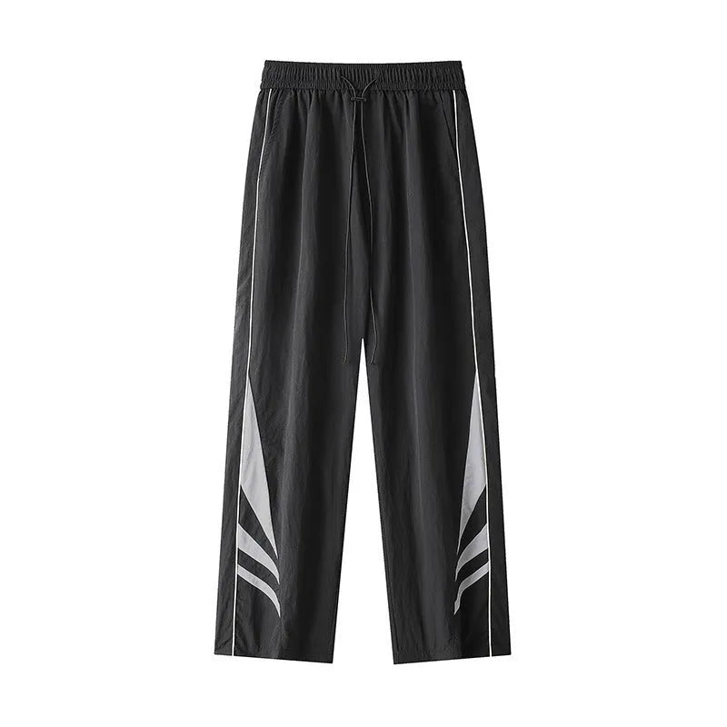 Men's black straight leg loose fit summer sports trousers with an elastic waist on a grey background.