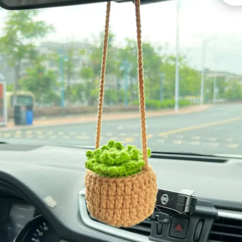 Green and white knitted wool car plant decoration with white hanging rope.