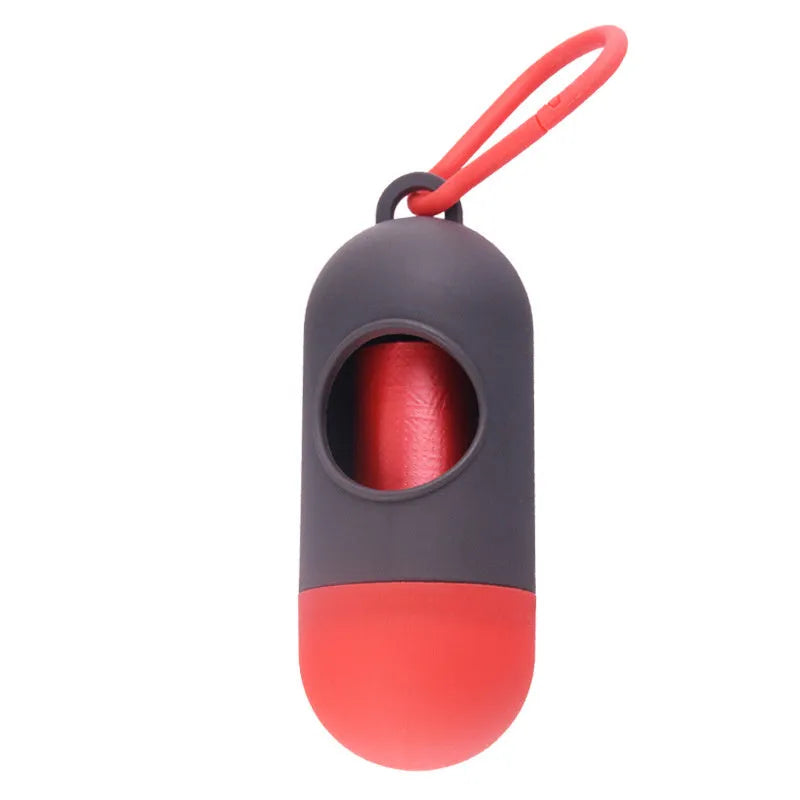 A small black plastic dog poop bag holder with a hook and Velcro strap, shown next to a roll of bags.