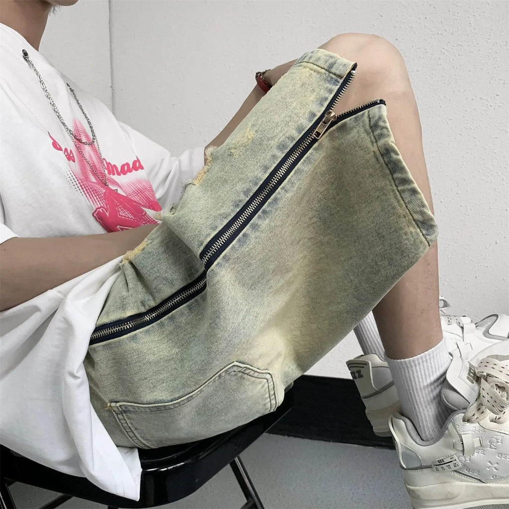 Men's blue denim shorts with yellow mud wash effect, ripping details, button fly, and loose straight-leg fit
