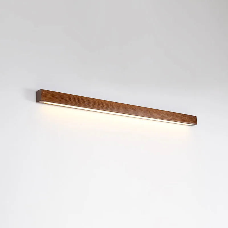 Walnut coloured log strip wall lamp with a square wood and acrylic profile mounted on a wall.