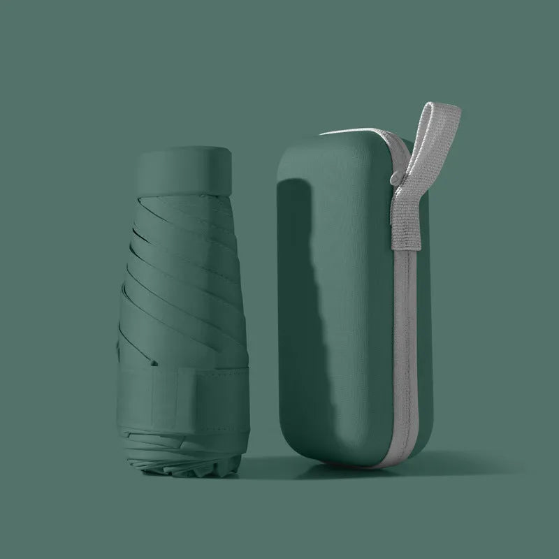 A folded six-fold flat umbrella in a capsule box, showing the steel ribs and rubber handle.