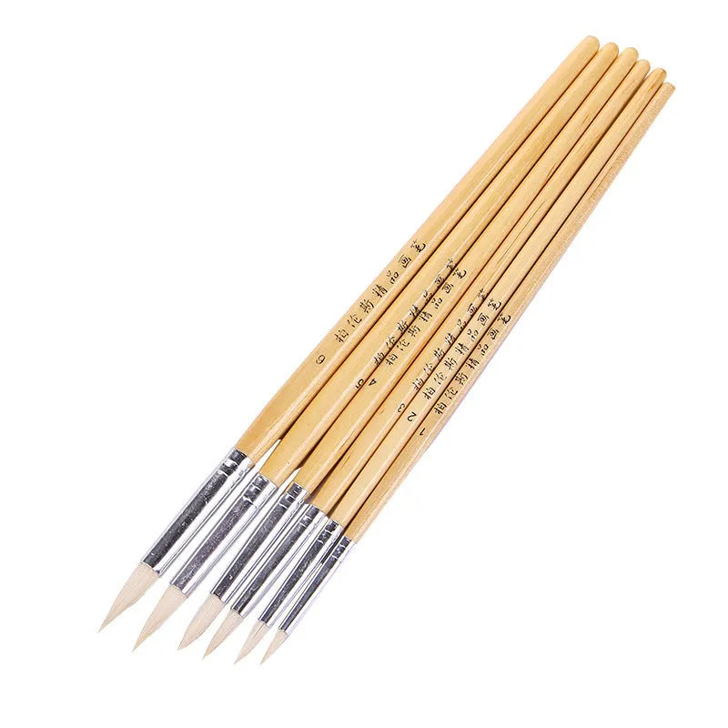 Six wooden pen brushes with pointed wool brush heads arranged as an artistic tool set