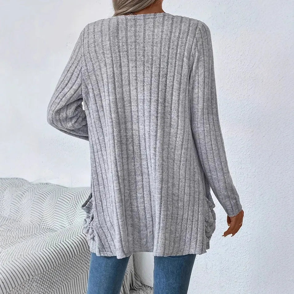 A grey loose fit long sleeve cardigan with pockets hanging on a hanger.