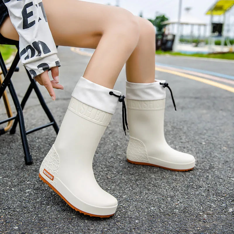 Women's solid colour PVC rain boots with non-slip sole in apricot, black, brown, or pink.