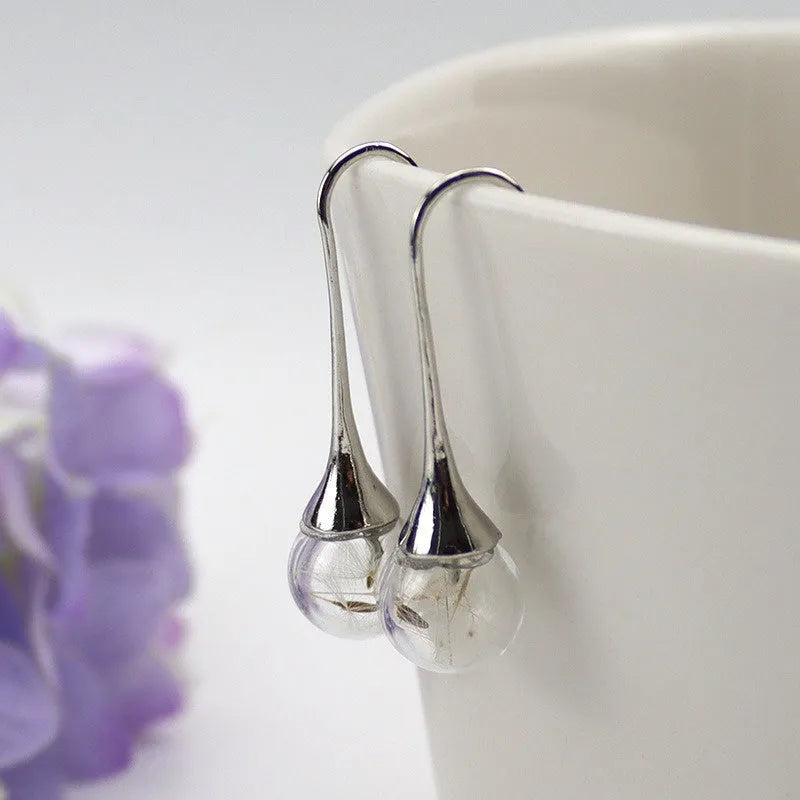 Transparent glass ball earrings on a French hook, showing dandelion seed design in silver and bronze finishes.