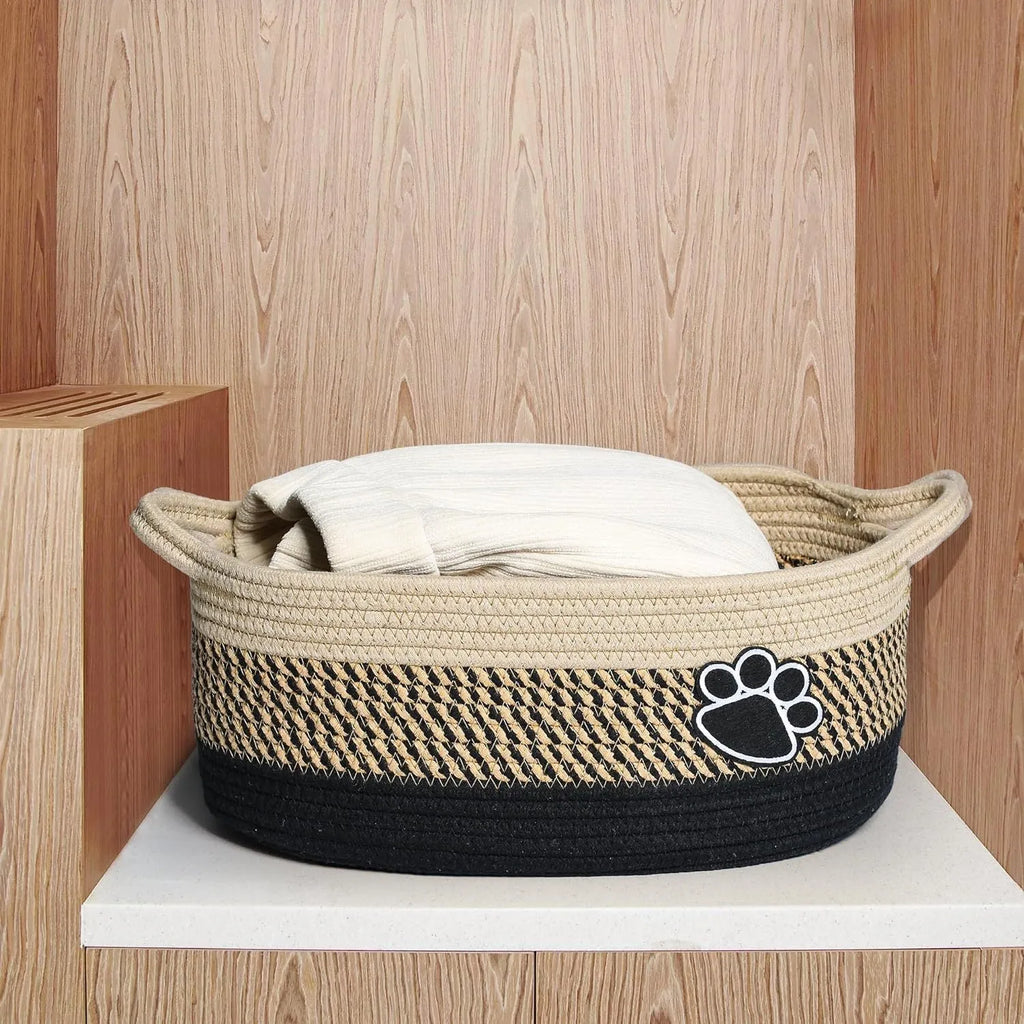Light beige handmade woven cotton rope storage basket with a handle on a wooden surface.