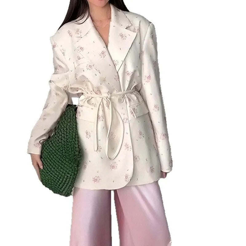 Women's white blazer with a lace-up fastening detail at the waist, shown on a hanger.