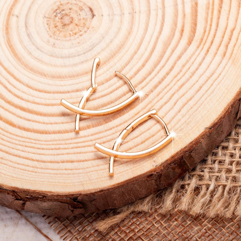 A pair of rose gold coloured cross-shaped earrings on a white background.