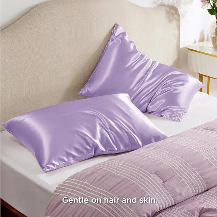 Pair of solid colour satin pillowcases in polyester fabric on a bed.