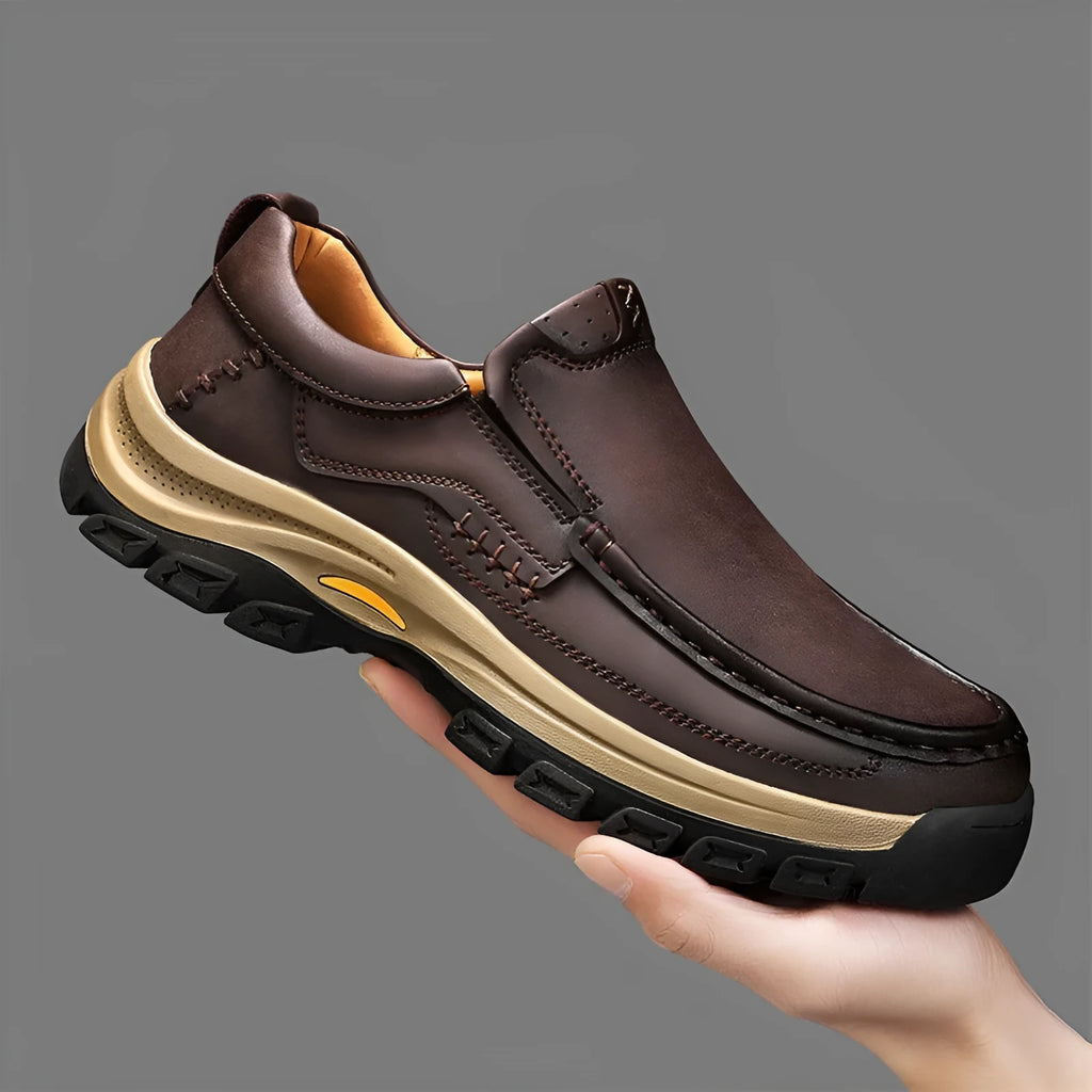 Men's black leather mountaineering shoes with thick rubber soles and round toe on a neutral background.