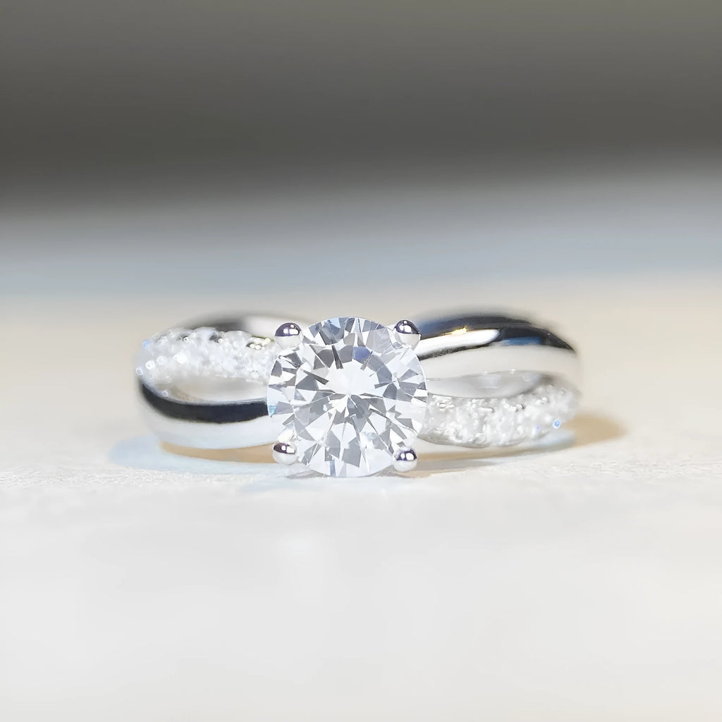 Silver moissanite ring with twisted arm band and four-claw setting holding 1 karat stone