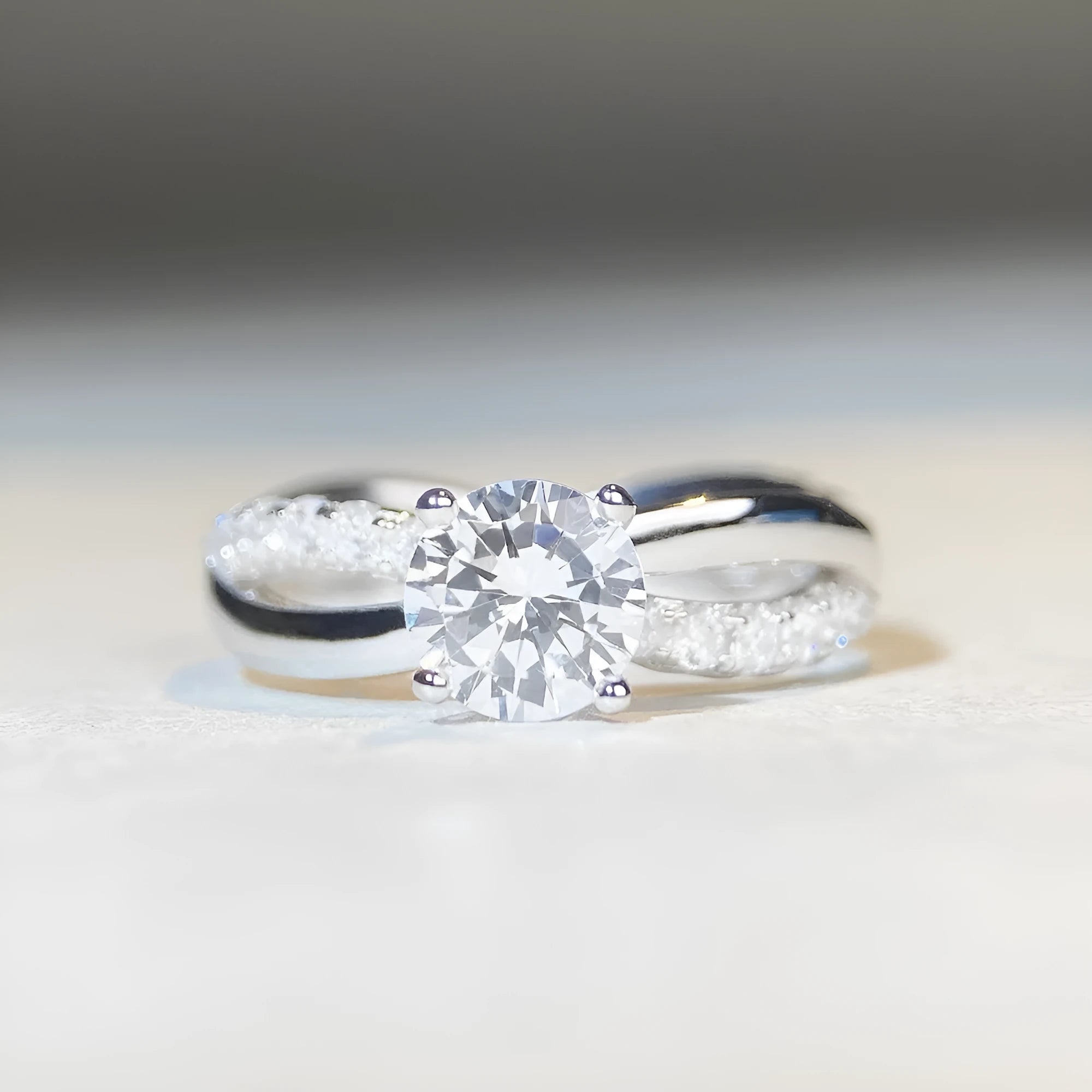 Silver moissanite ring with twisted arm band and four-claw setting holding 1 karat stone
