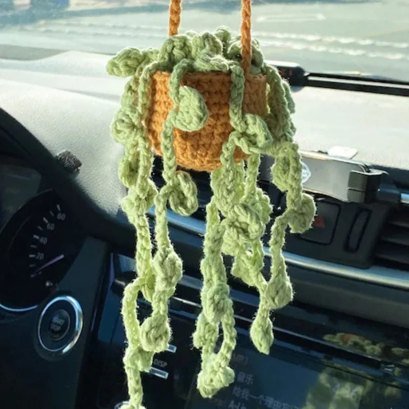 Green and white knitted wool car plant decoration with white hanging rope.