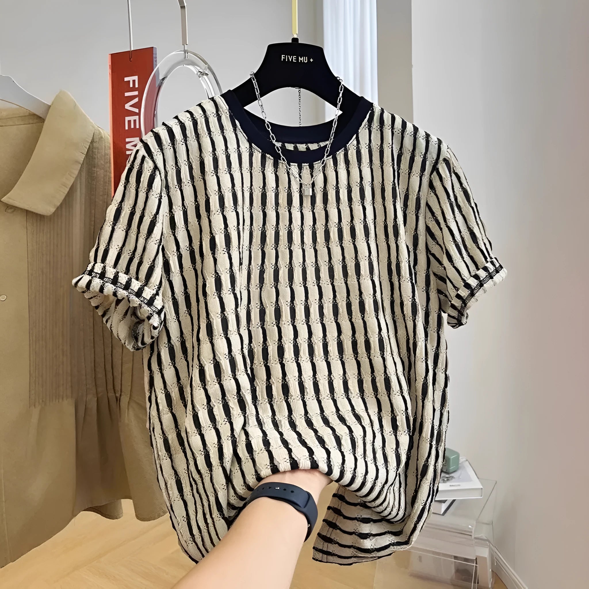Man wearing a black and white striped loose casual short sleeve shirt made from linen and silk blend.