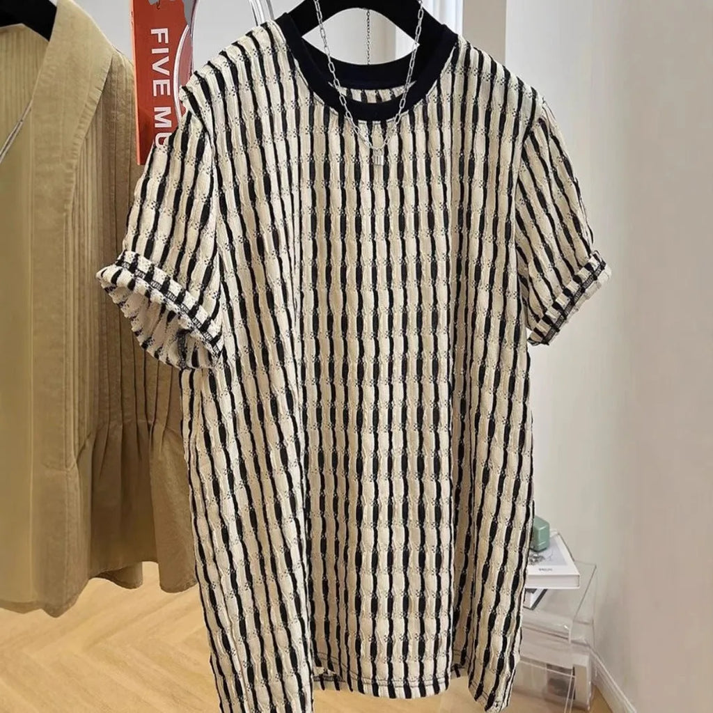 Man wearing a black and white striped loose casual short sleeve shirt made from linen and silk blend.