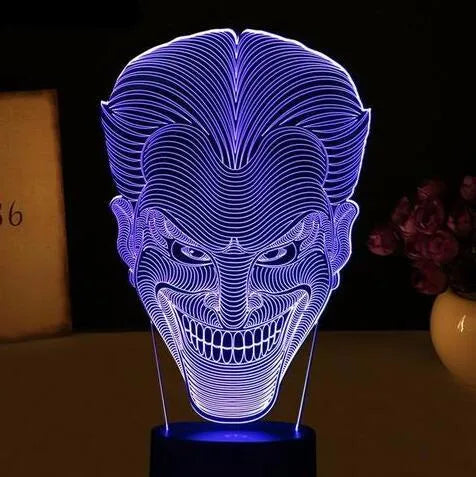 A clear acrylic 3D LED table lamp displaying gradient colours, standing on a square base with a USB cable and remote control.