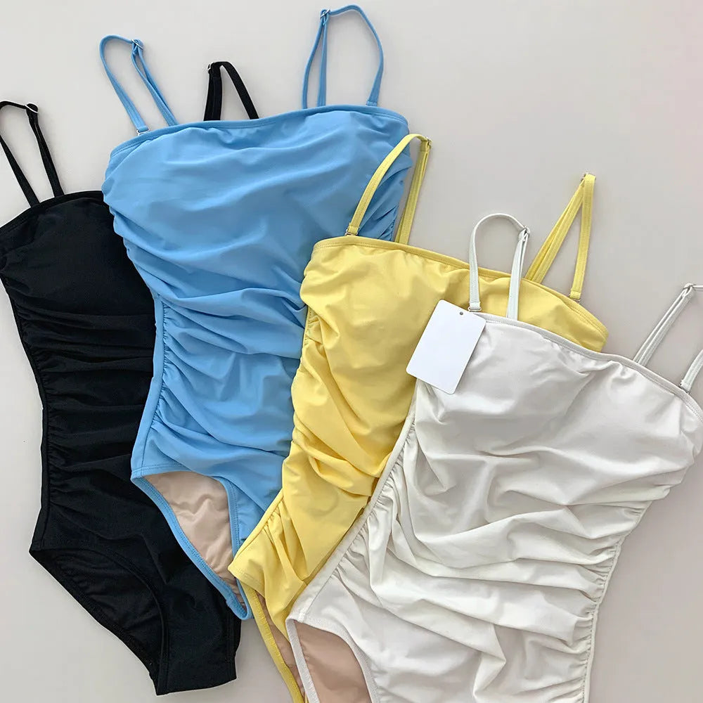 Blue sling style one-piece swimsuit with belly pleating on a mannequin