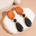 Brown-black wooden earrings with elliptical design and silver needle details for women