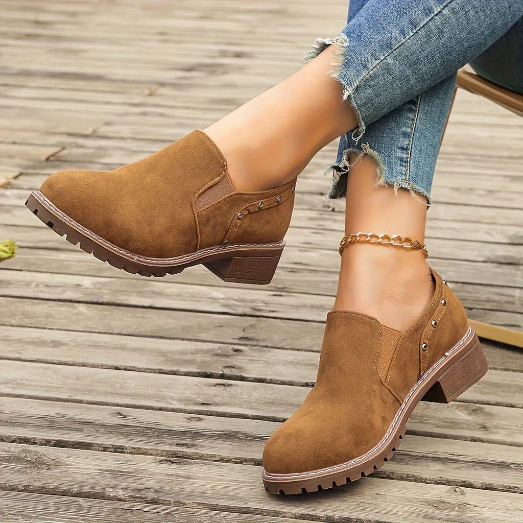 Women's light brown suede ankle boots with a low stout heel and elastic band at the ankle.